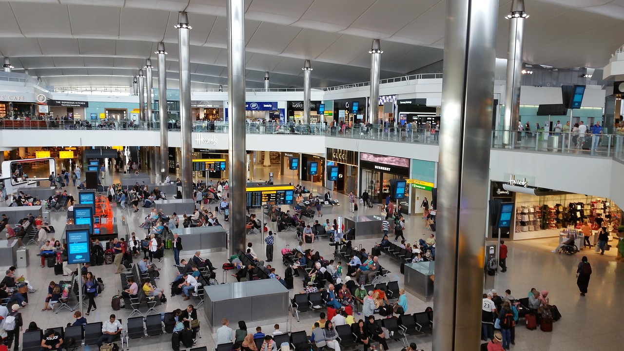 a crowded airport terminal hall seen from above, with travellers waiting at rows of seats