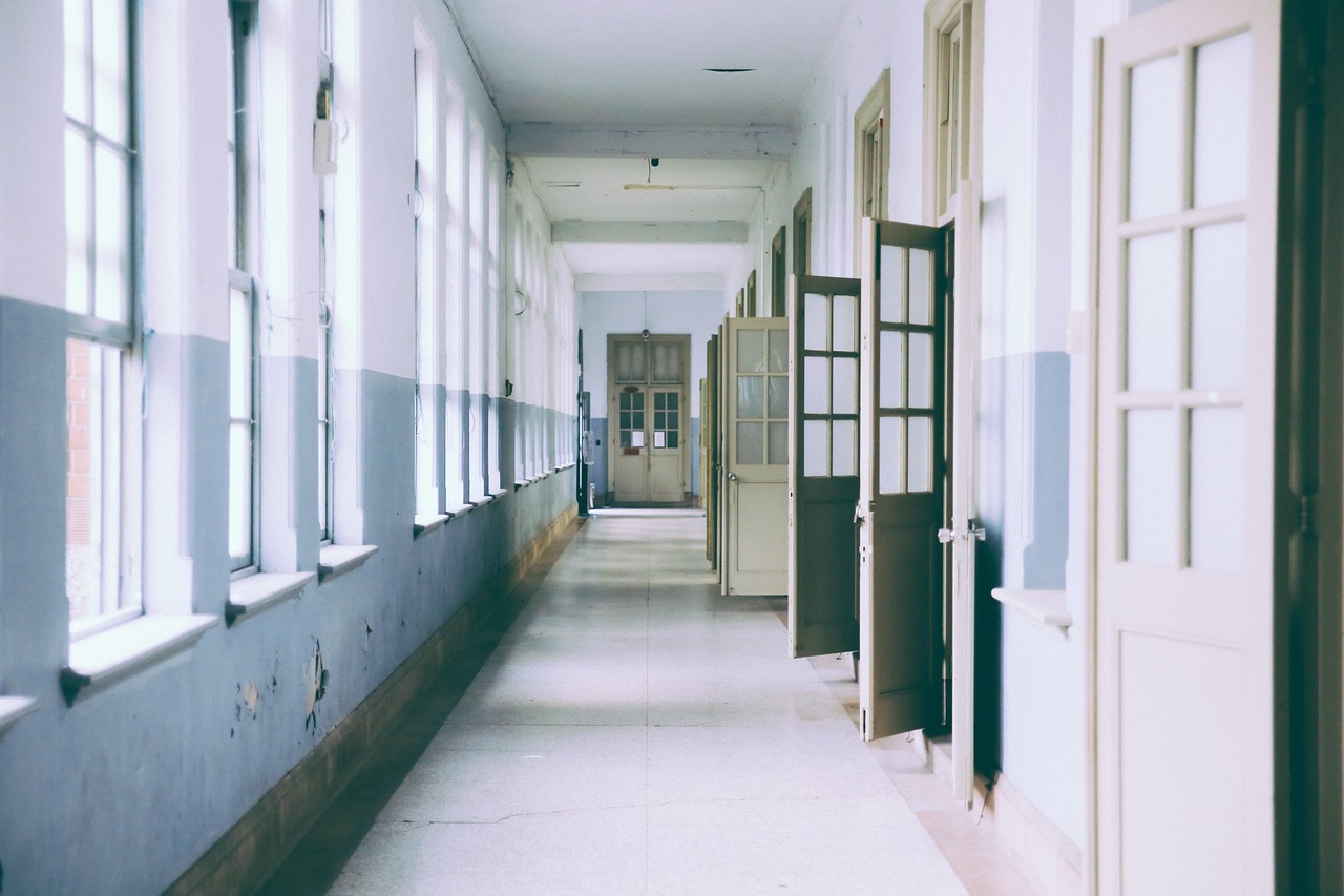 a long, empty school corridor, with classroom doors standing open