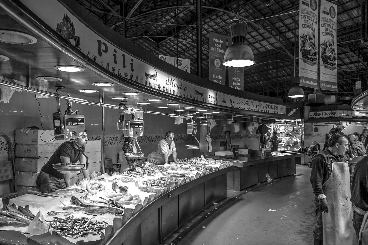 an indoor fish market, with traders behind the counter beneath hanging lamps
