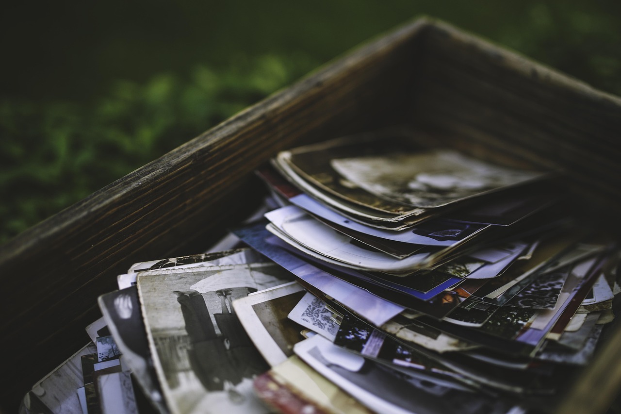 a close view of an old wooden box piled high with faded photographs