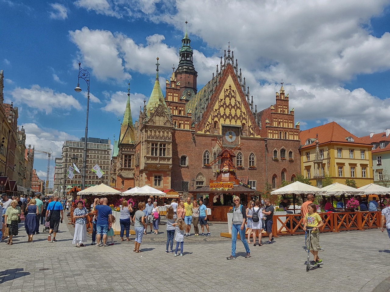 shoppers and families crossing a cobbled market square below a grand old town hall