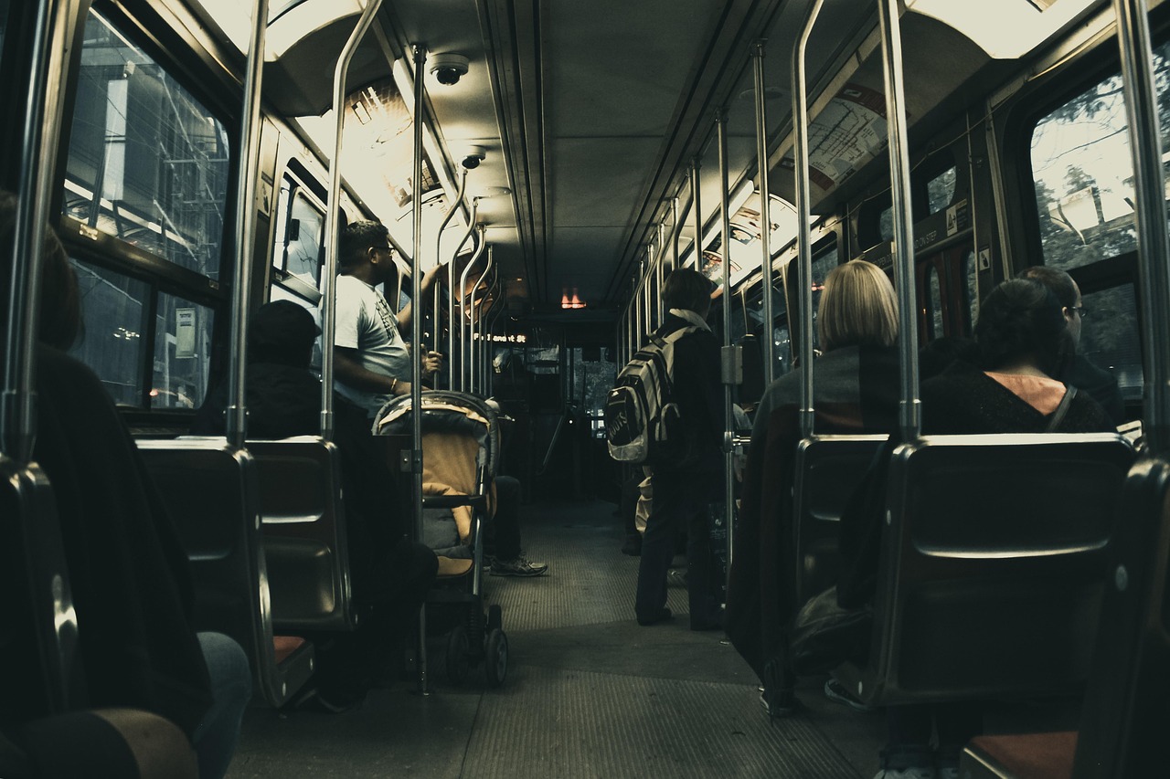 the dim inside of a city bus, with passengers sitting quietly and standing in the aisle